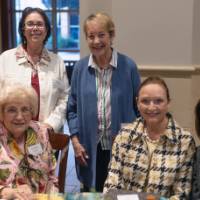 Small group of 5 event guests sitting at table, smiling for camera